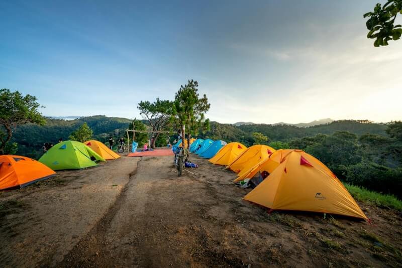 Campground with colorful tents placed on top of mountain in picturesque highlands on sunny day