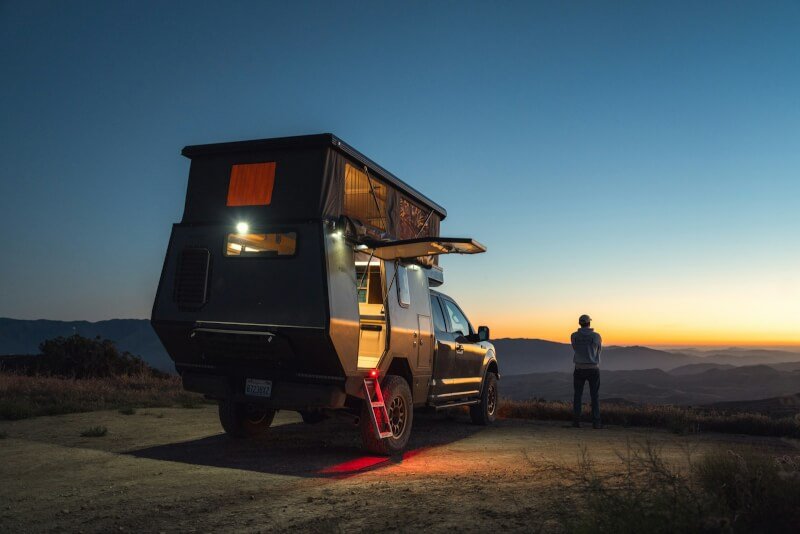 a man standing next to a truck with a camper on it