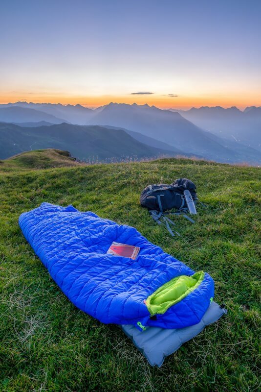 blue sleeping bag on mountain during daytime